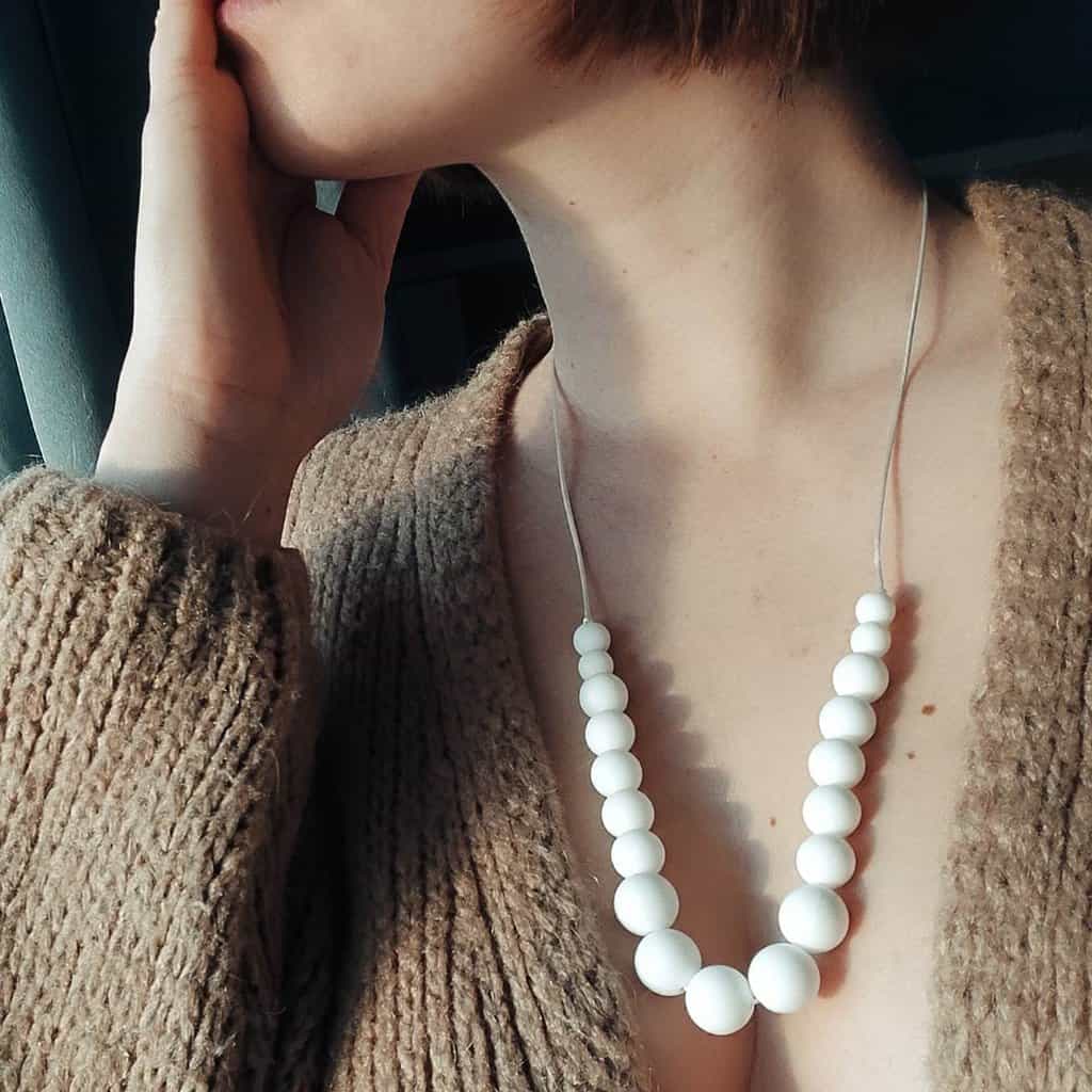 Collier d'allaitement Couleur blanc avec un fond en bois, 4 petites perles en silicone alimentaire de 9 mm, 8 moyenne perles en 12 mm et 5 perles en 15 mm.