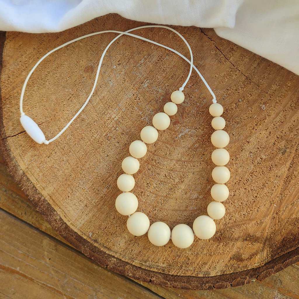 Collier d'allaitement Couleur crème avec un fond en bois, 4 petites perles en silicone alimentaire de 9 mm, 8 moyenne perles en 12 mm et 5 perles en 15 mm.
