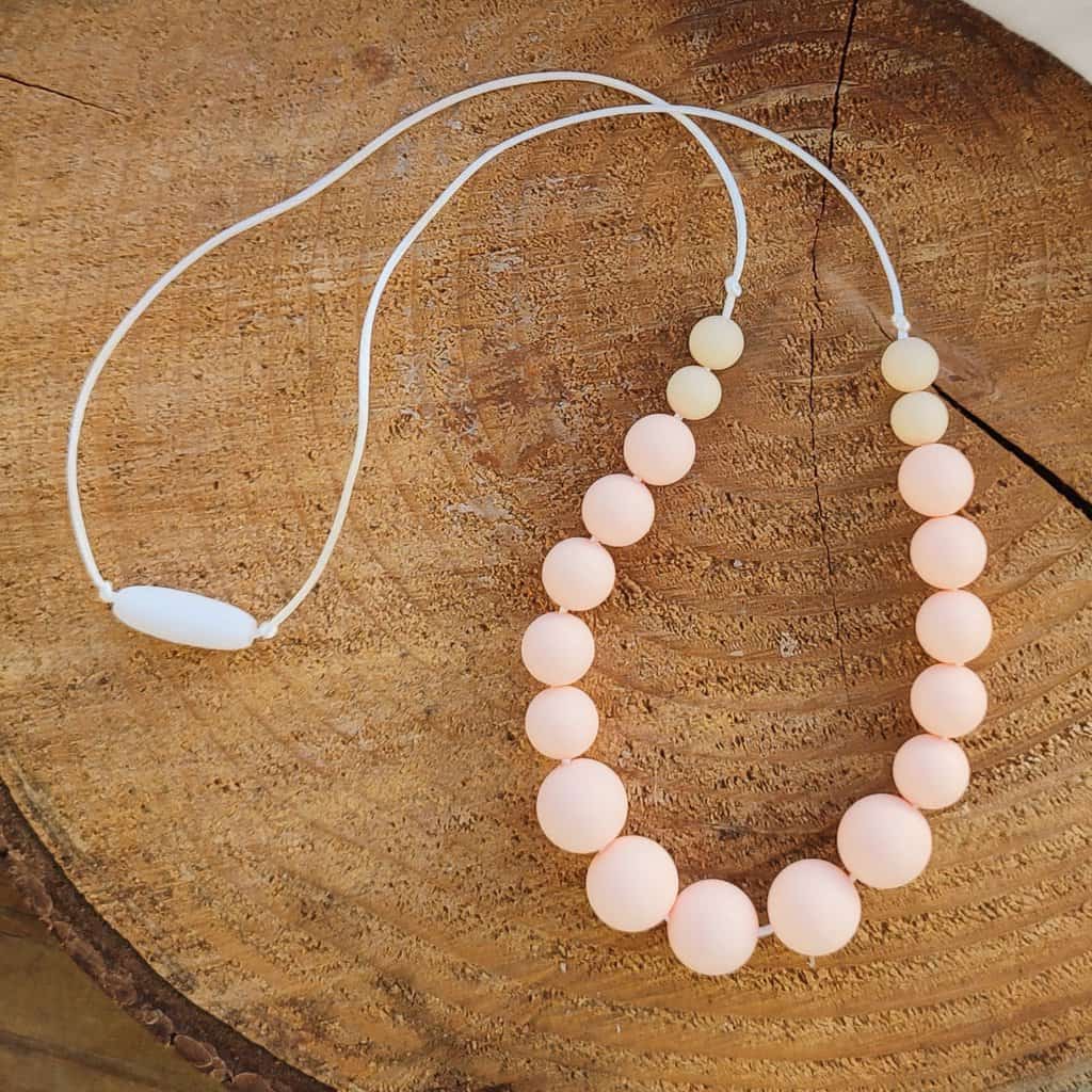 Collier d'allaitement Couleur lilas avec un fond en bois, 4 perles de 9mm sur les extrémités, 8 perles en silicone alimentaire en 12 mm et 5 perles en 15mm